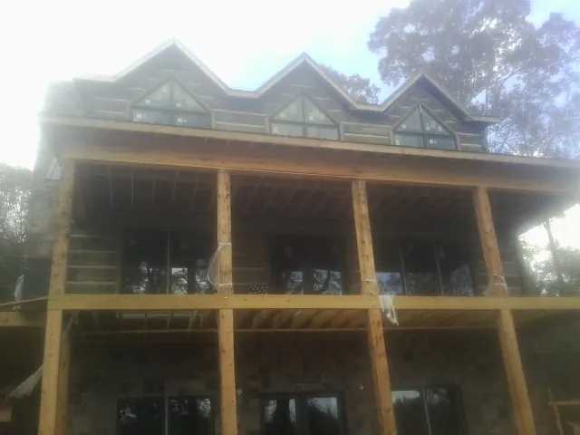 Dormers and porch framing on a large log home under construction — Roof Coating work by our crew in Garland