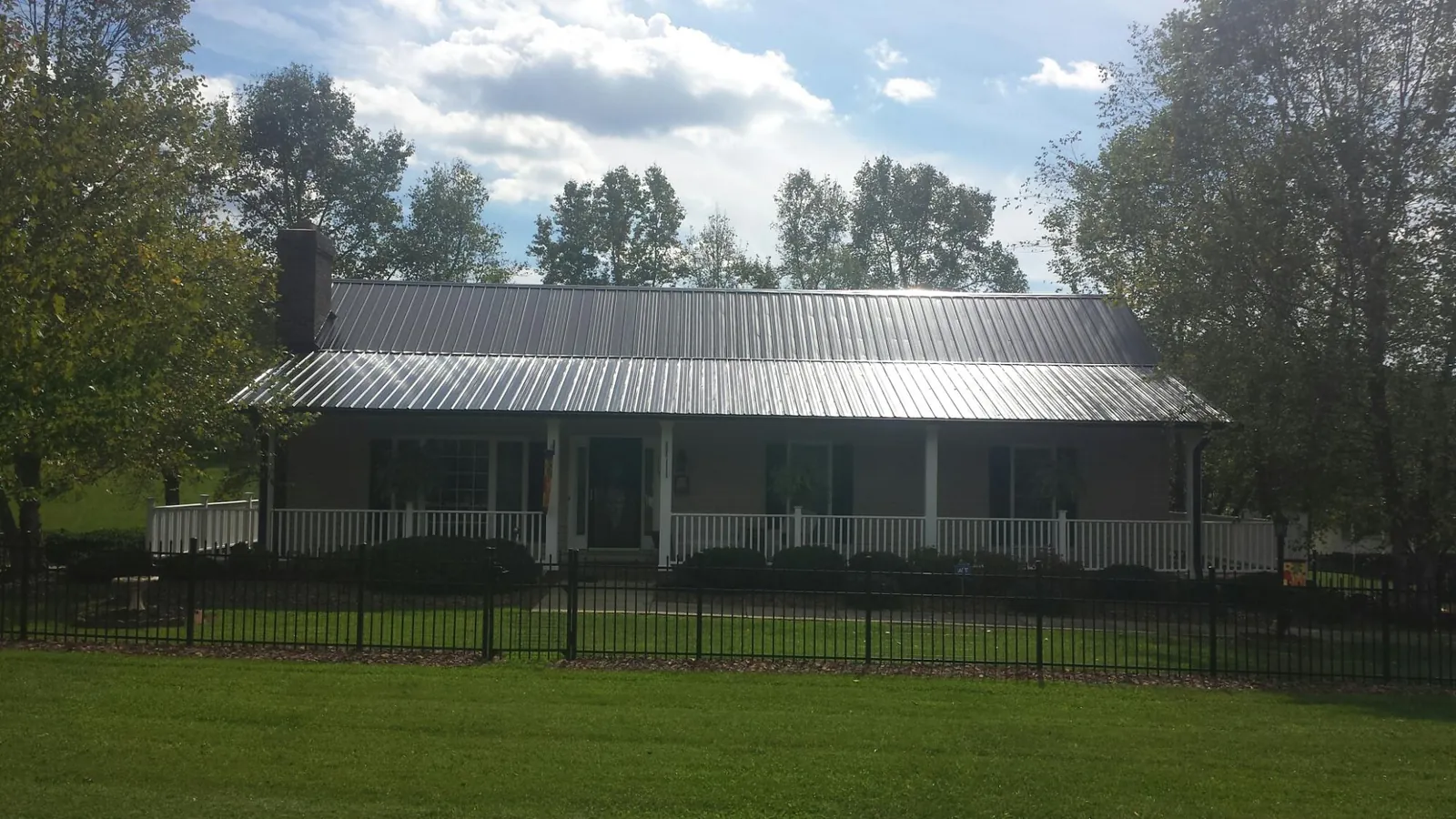 Gray metal roof on a brick ranch with a full width front porch — Gutter Guard Installation work by our crew in Garland